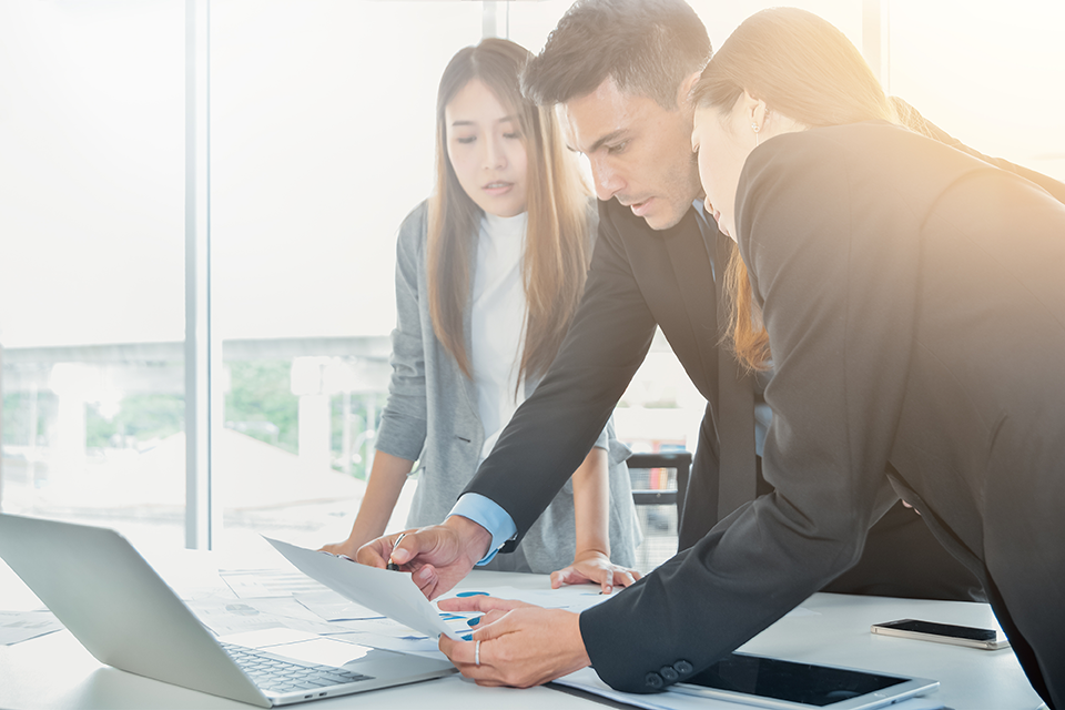 three people standing in front of laptop